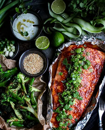 Ugnsbakad laxsida med honung och sriracha serveras med broccoli och en grön sriracha/koriandermajo