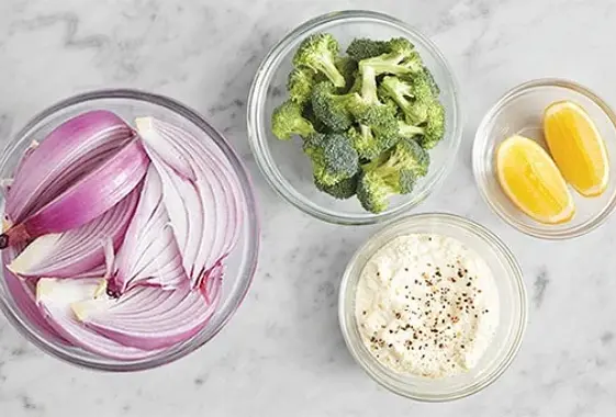Place an oven rack in the center of the oven; preheat to 450°F. Fill a medium pot 3/4 of the way up with salted water; cover and heat to boiling on high. Wash and dry the fresh produce. Cut off and discard the bottom 1/2 inch of the broccoli stem; cut the broccoli into small florets. Halve and peel the onion; cut into 1/2-inch-wide wedges. Using a zester or the small side of a box grater, finely grate the lemon to get 1 teaspoon. Quarter and deseed the lemon. In a bowl, combine the ricotta, lemon zest, the juice of 2 lemon wedges and a drizzle of olive oil. Season with salt and pepper.