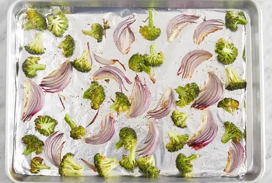 Line a sheet pan with foil. Place the broccoli florets and onion wedges on the foil. Drizzle with olive oil and season with salt and pepper; toss to coat. Arrange in an even layer. Roast 13 to 15 minutes, or until browned and tender when pierced with a fork. Remove from the oven.