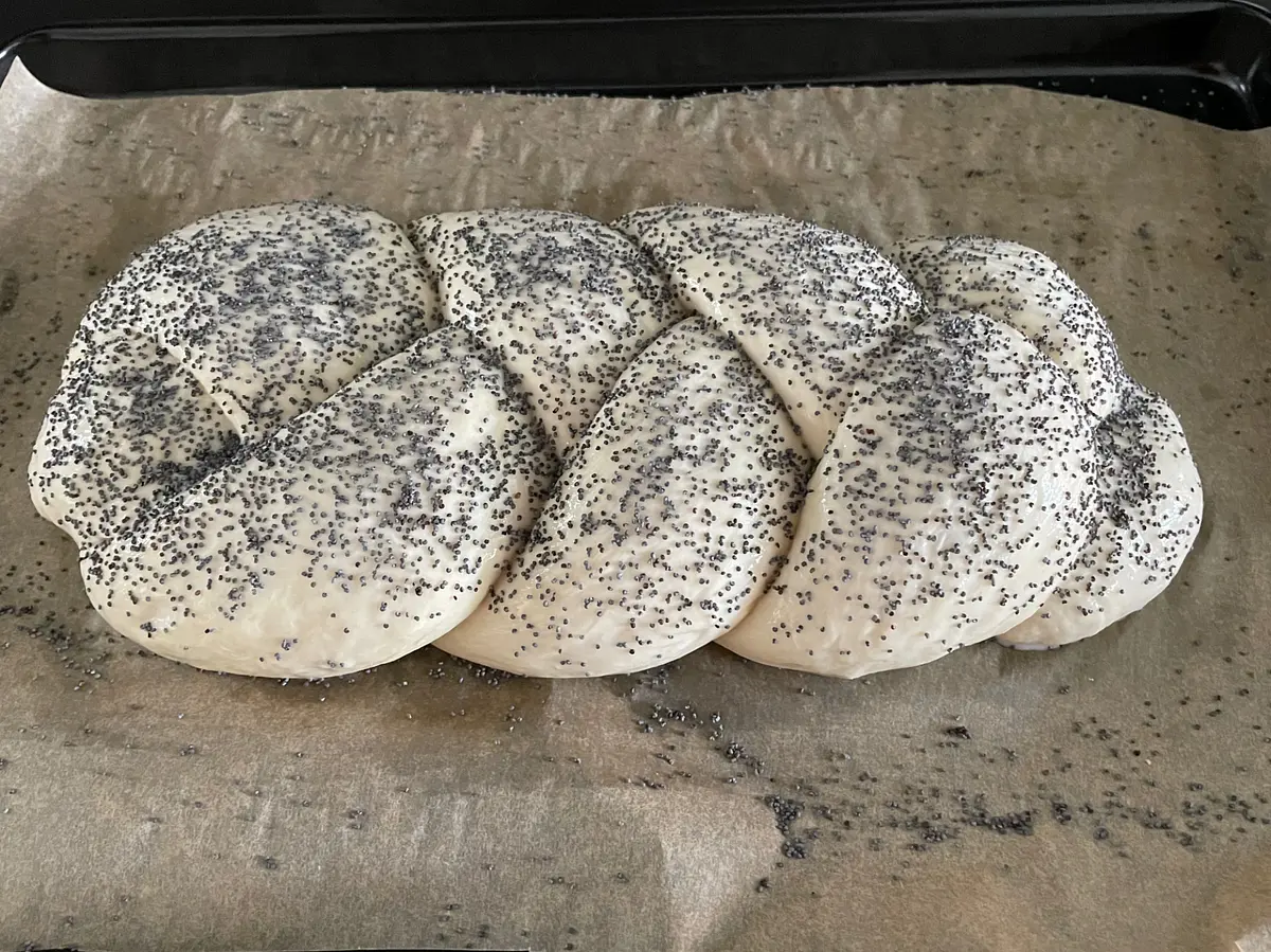 Once it’s done its second prove, your dough will now be looking nice and fat. Carefully remove the tea towel or cling film (it might stick a little), then brush it either with beaten egg, or with a little milk. Sprinkle it with a generous dusting of poppy seeds.