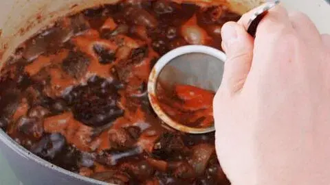 Add the red wine, beef stock, tomato paste, ketchup, chunou sauce, honey, and porcini powder, and return the beef to the pot. Bring the mixture to a boil. Use a skimmer to skim off any foam that rises to the surface until there isn’t much scum appearing.