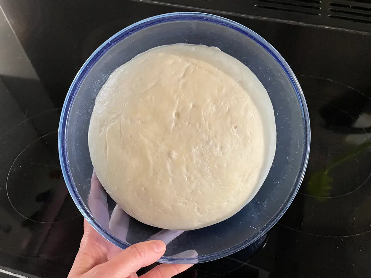 Get a couple of baking sheets or oven trays, line them with baking parchment, and give them a quick wipe with some more olive oil. Now that your dough has done its first prove, turn it out again on to a lightly floured surface, and knock it back. This basically means kneading it again lightly (some people like to “punch” it!) to knock the air out of it.