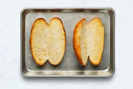 • While veggies cook, in a second small microwave-safe bowl, combine remaining garlic powder and 2 TBSP butter (4 TBSP for 4 servings); microwave until just softened, 10-15 seconds. Stir to combine and season with salt and pepper; set aside. • Slice baguettes lengthwise, stopping before you get all the way through; spread garlic butter onto cut sides. Place, cut sides up, on a second baking sheet. • Toast on middle rack until golden, 2-3 minutes.