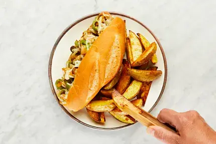 • Spread bottom halves of toasted garlic buns with half the garlic sauce. Top with chicken and veggie mixture, then sprinkle with mozzarella. Return to middle rack until cheese melts, 2-3 minutes. • Divide sandos and potato wedges between plates. Serve with remaining garlic sauce on the side.
