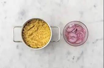 Préparez le bouillon dans la casserole. Ajoutez-y la semoule et 3/4 cc d’épices du Moyen-Orient, puis laissez gonfler 10 minutes à couvert. Égrenez à la fourchette. Enfournez la courgette et le poivron 6 à 8 minutes. Pour la marinade, faites chauffer 50 ml d'eau par personne dans la petite casserole. Ajoutez-y, par personne : 1/2 cs de sucre et 2 cs de vinaigre de vin blanc. Retirez du feu. Coupez l'oignon rouge en demi-rondelles. Ajoutez-les à la marinade et réservez jusqu’à utilisation.