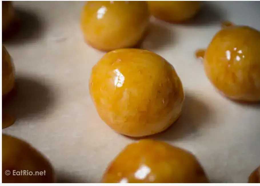 Now you want to coat the coconut centres with the sugar mixture. Be careful bc that sugar is seriously hot. Take each coconut ball and dip it into the hot sugar mixture using either a tsp or a cocktail stick. Once fully coated, allow some of the excess sugar to drop off, then place the ball on a greased surface or a piece of parchment paper.