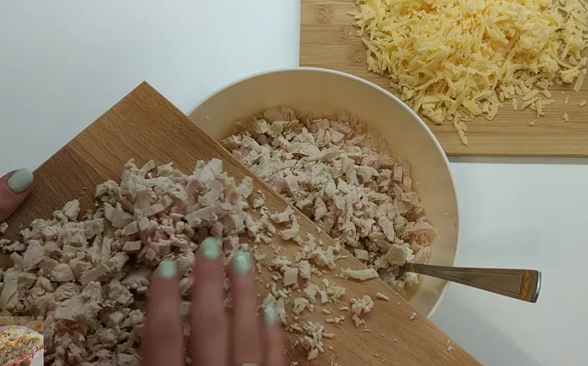 Отварное куриное филе мелко нарезаем, добавляем к творогу, туда же натертый сыр, сметану, выдавленный чеснок и все приправы.
