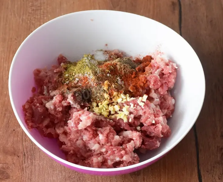 В миске соедините рубленое мясо с салом, лук, чеснок, специи и соль.