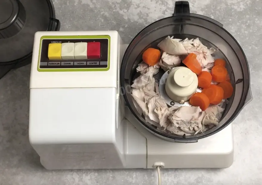 Готовое мясо отделите от костей и порежьте на куски. Сложите мясо и овощи, с которыми оно варилось, в чашу блендера.