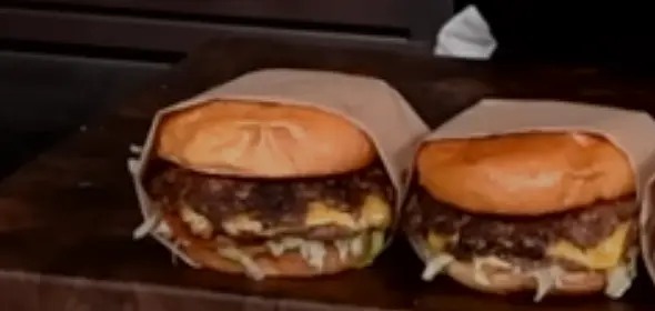 Make a triangle with paper by folding it in half diagonally, fold corners under the burger and then tuck in the 3rd corner into the back