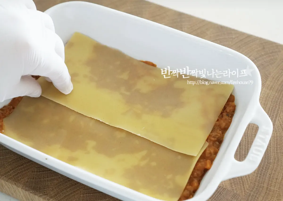 오븐 용기에 녹인 버터를 골고루 발라주고 라구를 넓게 골고루 펼쳐 바르고 그 위로 라자냐면을 올려줍니다