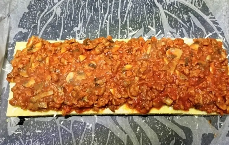 Мясное рагу разделить на три части. Лист поленты посыпать тертым сыром и выложить соус,