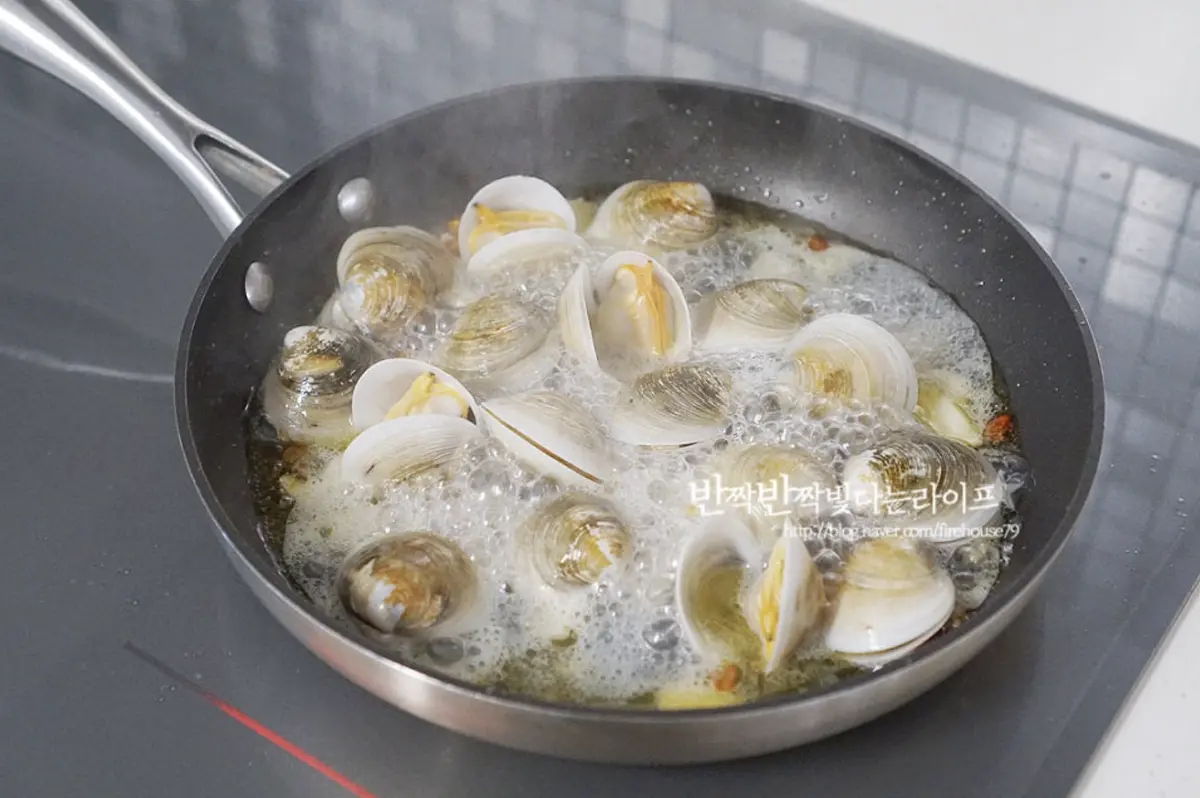 마늘의 향긋함이 느껴지면 모시조개를 넣어줍니다. 조개와 함께 화이트와인 3 큰 술, 면수 60ml를 부어 알코올을 날려가며 익혀줍니다.