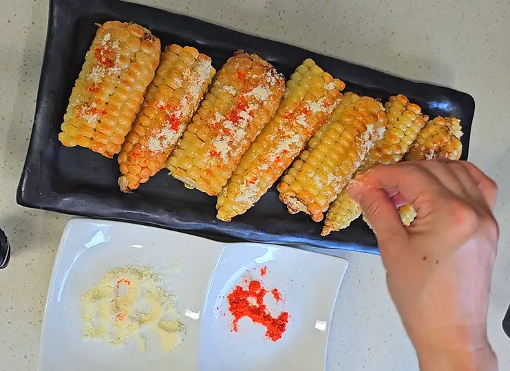 파프리카 가루, 파마산 치즈 가루, 파슬리 가루를 옥수수 위에 뿌려줍니다.