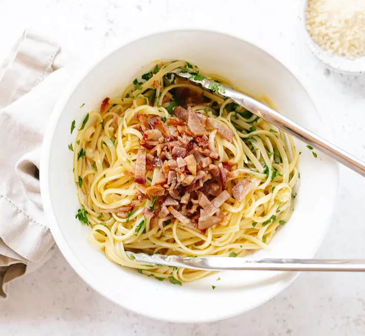 Dump the hot cooked pasta into the bowl and toss immediately and quickly with tongs until thoroughly mixed. Sprinkle the chopped bacon and parsley over and toss again.