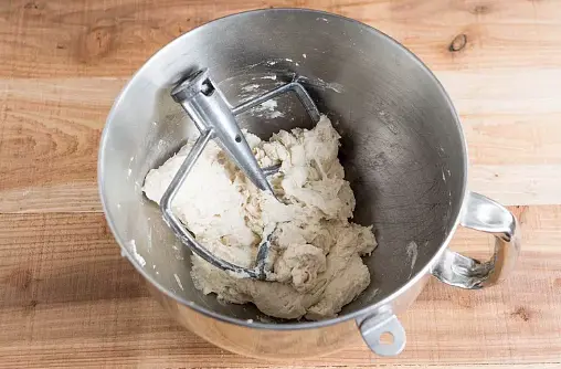 In a stand mixer with the paddle attachment, combine the flour, yeast, and salt on low speed. Add the water all at once and mix until the dough comes together and cleans the sides of the bowl, about 30 to 60 seconds. You don't need to knead it, just get all the ingredients mixed together. The dough will be soft and slightly sticky, with no more visible streaks of flour on the surface. To mix by hand, follow the same procedure using a large bowl and a wooden spoon.