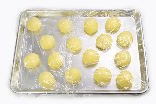 When the DOUGH course completes, remove the dough and divide into 16 for the 2-lb. breadmaker, or into 10 for the 1-lb. breadmaker, and shape each piece into a ball. Cover with a plastic wrap and let rest for 20 minutes.