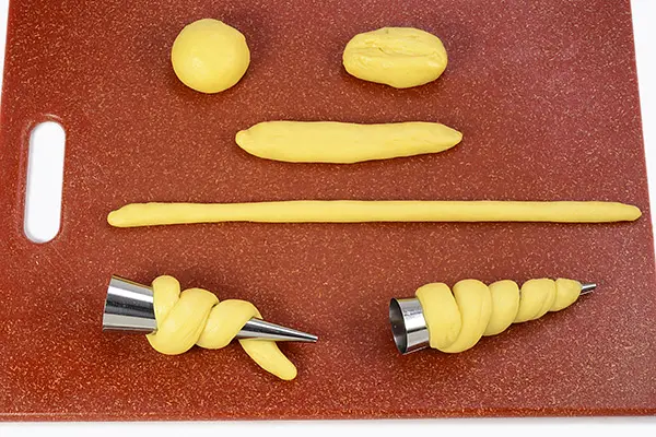 Shape doughs into horns. Grease each mold with butter(not in the ingredients) and set aside. Roll a dough into 12” long rope. Starting at the wide end of the mold, wrap dough around the mold, not too tightly, with 1/8” space between dough seams, to allow room for proofing. Tuck both ends under the dough spiral to keep dough from unraveling.