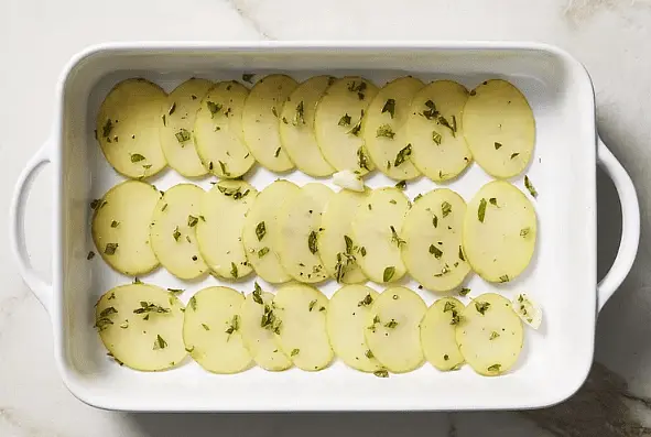 Arrange potatoes in a 9-by-13-inch baking dish, overlapping them; top with tomatoes.