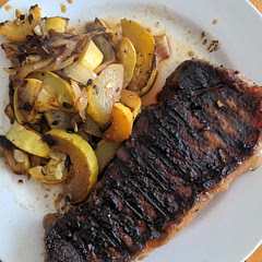 New York strip served with summer squash and onions