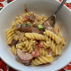 Cut sausage in half, then slice it 
Cook pasta per directions on box