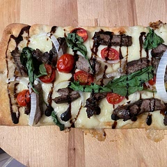 Honey spread on flat bread, mozzarella discs, steak, tomato, onion, spinach. Then topped with balsamic drizzle when done baking
