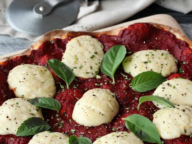 You could try using cashew cheese. We're not fond of that fake cheese taste as a family, but we all like the mild nuttiness of cashew cheese on our pizzas and on salads. Bear in mind that it doesn't melt, but does brown slightly!