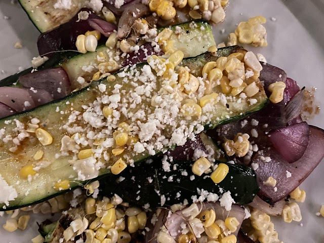 Grilled zucchini, red onion, and corn with cotija and a spicy sunflower oil dressing 🤤