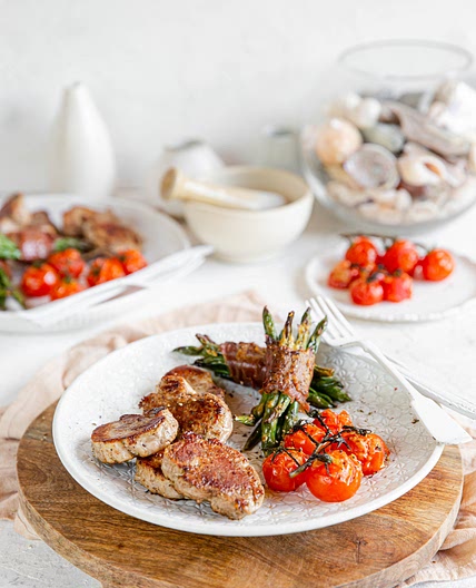 Pan-seared pork loin with bacon-wrapped green beans and baked tomatoes