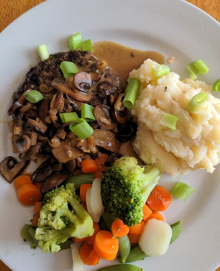Angus Steakhouse Patty with Mushroom Cream Sauce, Loaded Mashed Potatoes, and Mixed Veg