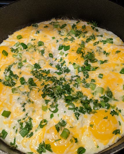Fried eggs with green onions, parsley, & cheese
