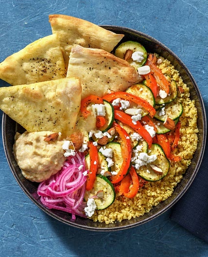 Bowl au baba ganoush avec semoule et fromage grec, oignon rouge mariné, légumes rôtis et amandes
