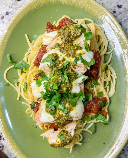 Mozzarella tomato pesto chicken over pasta