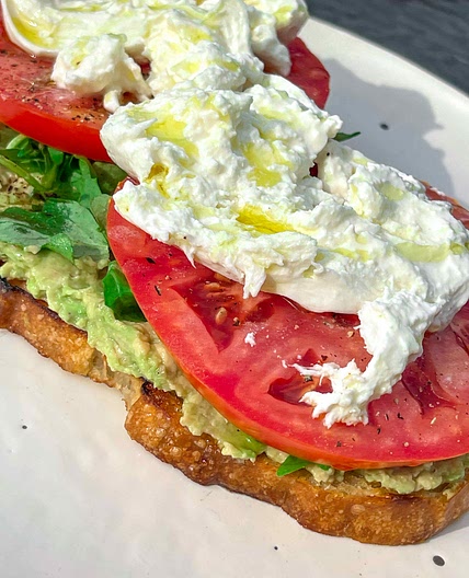 Avocado toast with tomatos and burrata.  