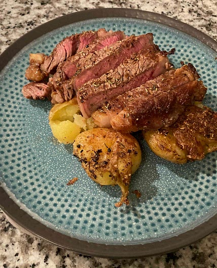 Cast iron seared steak over parmesan crusted smashed potatoes 