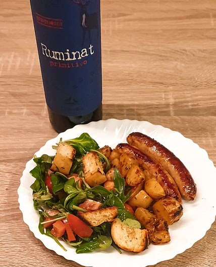 Salade de panzanella italienne accompagnée d'une saucisse et des pommes de terres épicées