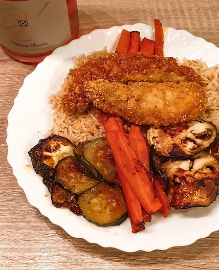 Poulet en croûte de sésame accompagné de légumes rôtis et de riz.