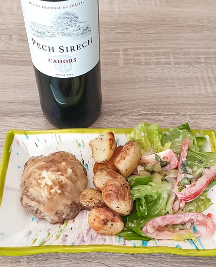 Burger de veau accompagné de grenailles poêlées, garni de cornichons et de cheddar fondu