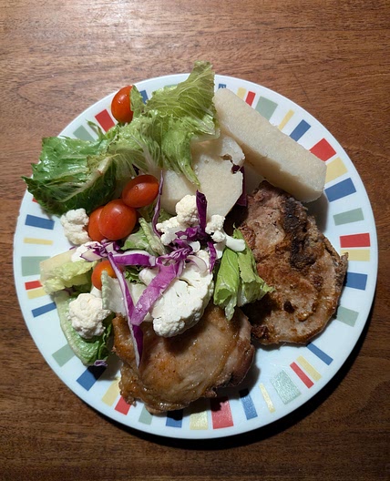Pork chop, chicken thigh, and yam with lettuce, cauliflower, purple onion, and baby tomatoes