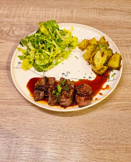 Steak en sauce à l'oignon, pommes de terre et salade de concombre
