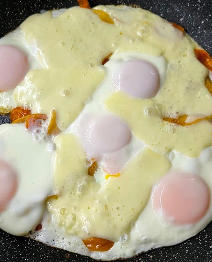 Scrambled eggs with tomatoes, meat, and cheese