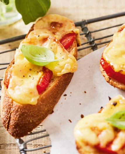 Überbackenes Brot mit Käse, Tomaten und Basilikum