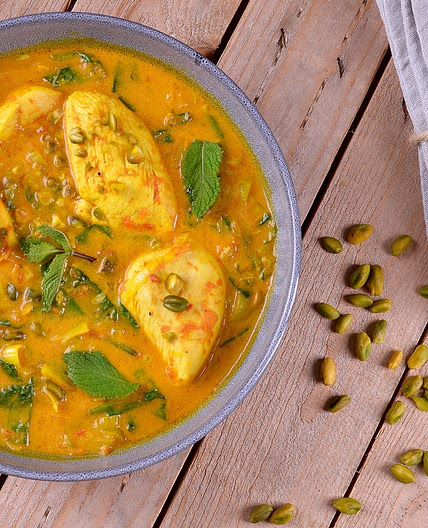 Pollo guisado con cúrcuma, hojas verdes y pistachos