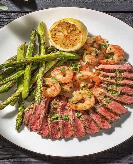 Surf and Turf: Sirloin Steak and King Prawns with Wedges, Asparagus and a Charred Lemon and Garlic Butter