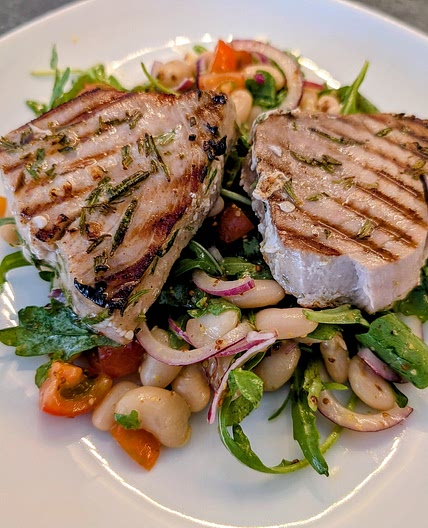 Griddled marinated tuna steaks with beans, tomato, rocket and red onion salad