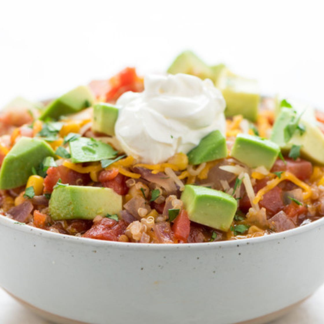 Tex-Mex Quinoa Vegetable Stew with avocado and cheddar-jack cheese