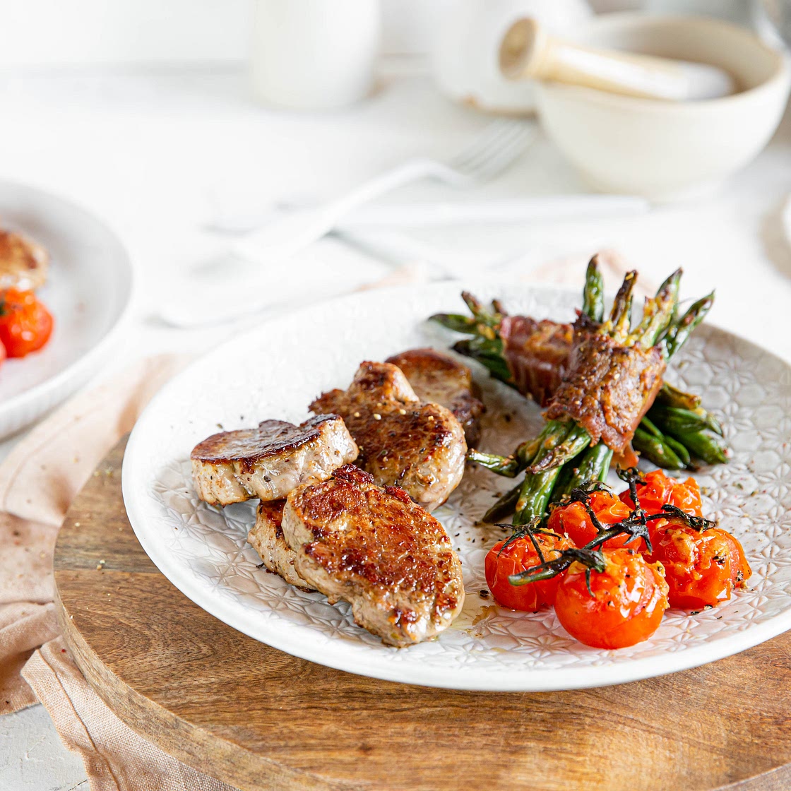 Pan-seared pork loin with bacon-wrapped green beans and baked tomatoes