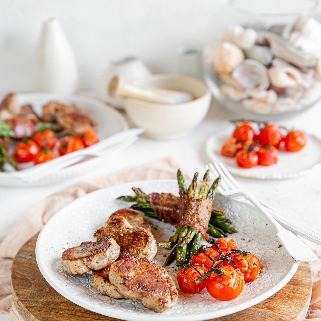 Pan-seared pork loin with bacon-wrapped green beans and baked tomatoes