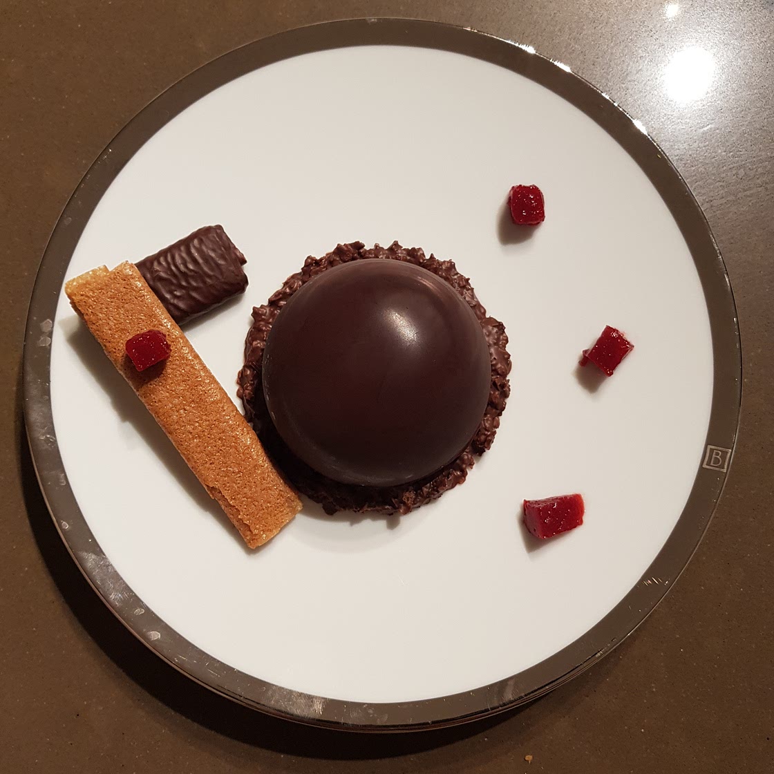 Dôme de chocolat, mousse au chocolat au cœur de framboises sur son croustillant pralinoise