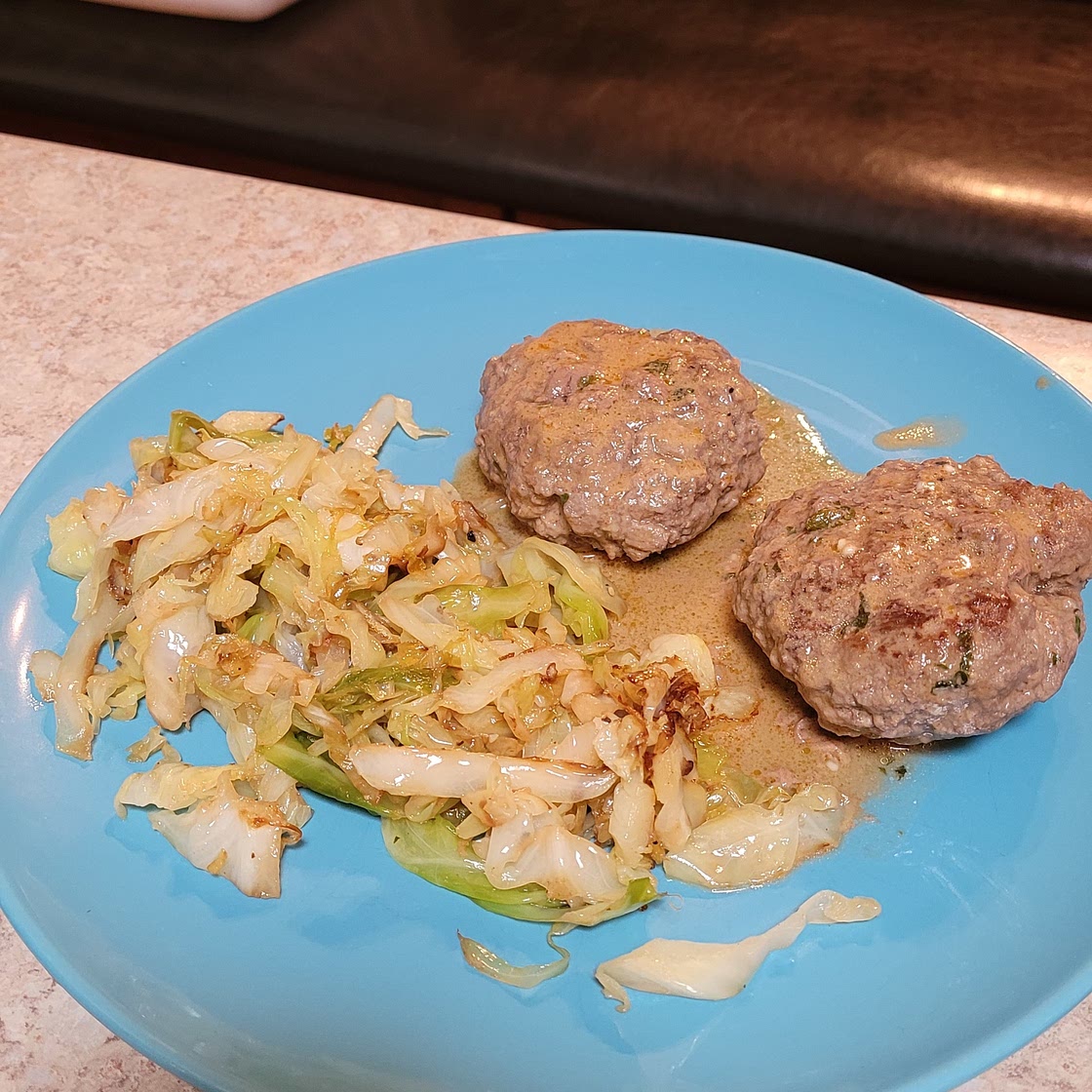 Keto hamburger patties with creamy tomato sauce and fried cabbage